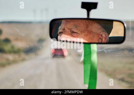 View from the rearview mirror of a car of an elderly man driving Stock Photo