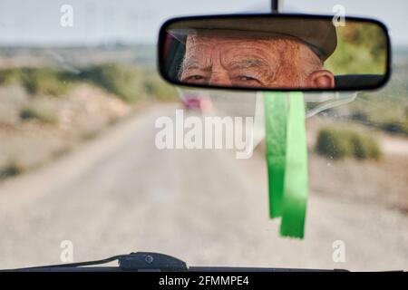 View from the rearview mirror of a car of an elderly man driving Stock Photo