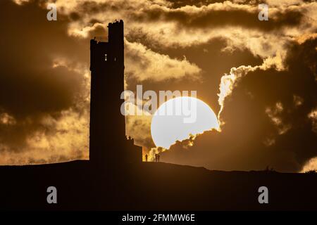 People watch the sun set over Victoria Tower, Castle Hill, Huddersfield. The tower was built to commemorate Queen Victoria's Diamond Jubilee of 1897 however the history of human activity on the Castle Hill dates back over 4000 years Stock Photo