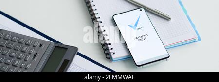 On table lies a smartphone with inscription payment sent documents and calculator Stock Photo