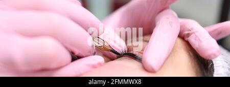 Master performs permanent makeup on eyelids by making decorative arrow Stock Photo