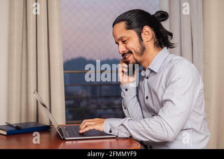 Young latin man working at home in the living room Stock Photo