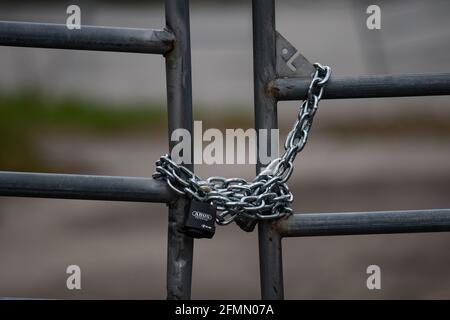 A metal gate closed with heavy chain and two padlocks. Stock Photo