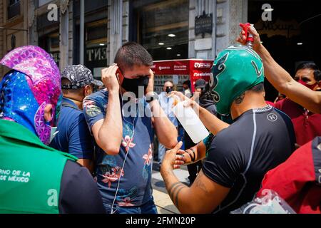 Mexico, Mexico. 10th May, 2021. Mexican Luchador distribute antibacterial gel to people. 'The Brigade two of three falls' called by the Mexican City Youth Institute made a round of Madero Street in the Historic Center encouraging the use of face masks since the pandemic still continues despite the epidemiological yellow traffic light. Credit: SOPA Images Limited/Alamy Live News Stock Photo