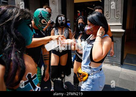 Mexico, Mexico. 10th May, 2021. Mexican Luchadores distribute antibacterial gel to people. 'The Brigade two of three falls' called by the Mexican City Youth Institute made a round of Madero Street in the Historic Center encouraging the use of face masks since the pandemic still continues despite the epidemiological yellow traffic light. (Photo by Guillermo Diaz/SOPA Images/Sipa USA) Credit: Sipa USA/Alamy Live News Stock Photo