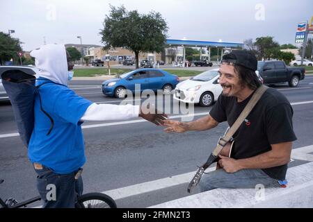 Musician and handyman Douglas Crawford, right, greets a street buddy as he strums his guitar for spare change near his camp at the corner of Ben White Blvd. and south Congress Avenue in Austin, TX where he's lived for over a year. Crawford, 60, says he stays to himself and isn't worried about Austin's new homeless crackdown and camping ban starting Tuesday. ©Bob Daemmrich Stock Photo