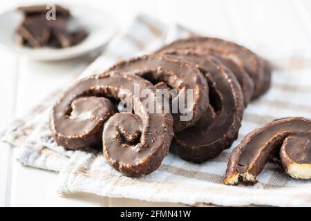 Sweet pastry palmeritas with chocolate icing on white table. Stock Photo