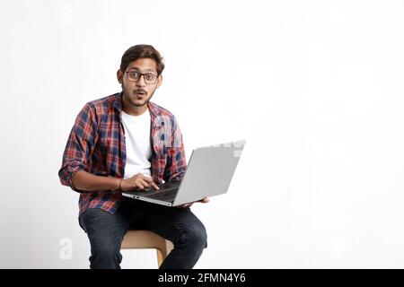 Young indian man using laptop and giving surprised expression. Stock Photo