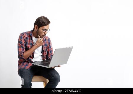 Young indian man using laptop and giving surprised expression. Stock Photo