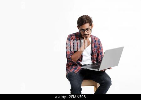 Young indian man thinking some idea when working on laptop. Stock Photo