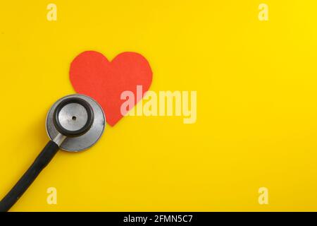 A heart with a stethoscope on yellow background. Stock Photo
