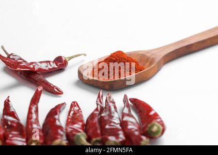 Chilli powder in wooden spoon with dry red chilly on white background. Stock Photo