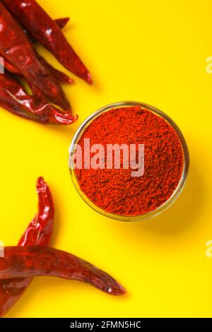 Dry Red chilli with chilli powder in glass bowl on yellow background.