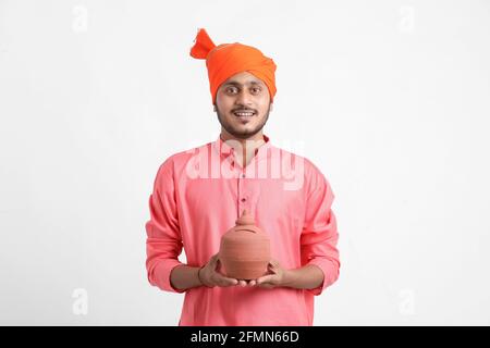 Indian Farmer holding piggy bank on white background Stock Photo