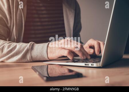Freelance worker using laptop computer at home office desk, close up with selective focus Stock Photo