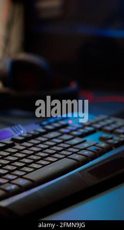 Close up of professional RGB keypad in empty gaming room prepared for streaming online tournament, display with first person shooter playing on it. Game studio with powerful computer Stock Photo