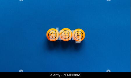 Various emoticons made of orange table tennis balls drawn lines of a mouth. Over blue background in a conceptual image of quality and feedback. Stock Photo