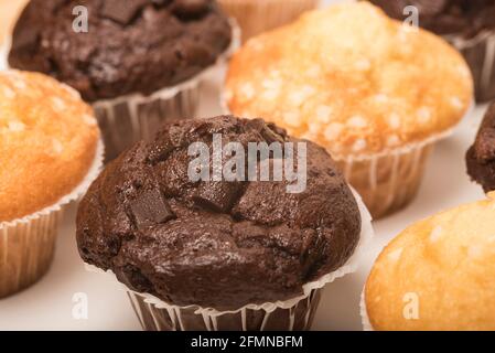 Chocolate muffins with chocolate chunks and lemon muffins decorated with sugar crystals on a white background. Teatime treat. Stock Photo