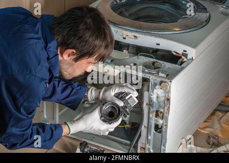 Mechanic or technician is repairing old washing machine. Stock Photo