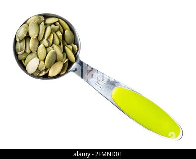 top view of peeled pumpkin seeds in measuring spoon cutout on white background Stock Photo