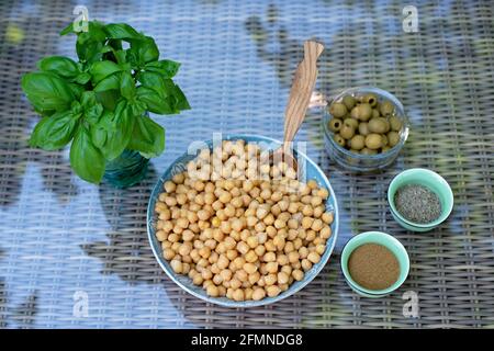 A set of ingredients for the preparation of hummus pesto with olives: chickpeas, spices, olive oil, fresh basil. Recipe for a vegetarian Mediterranean Stock Photo