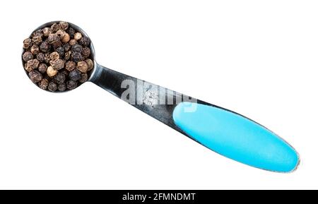 top view of black pepper peppercorns (cooked and dried unripe piper nigrum fruits) in measuring teaspoon cutout on white background Stock Photo