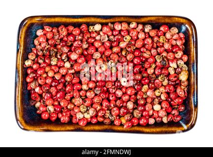 top view of pink peppercorns (Baie rose) in ceramic bowl cutout on white background Stock Photo