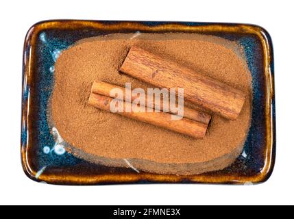 top view of cassia bark and cinnamon powder in ceramic bowl cutout on white background Stock Photo