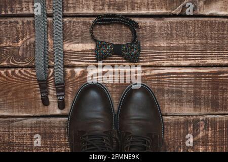 Father's day with men's accessories suspenders and bow-tie and leather shoes on a wooden background. Copy space. Flat lay. Stock Photo