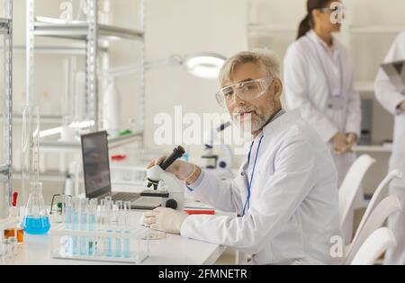 Portrait of a successful experienced senior scientist working under a microscope in a laboratory. Stock Photo