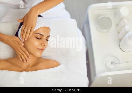 Cosmetologist making professional manual relaxing rejuvenating massage for young woman Stock Photo