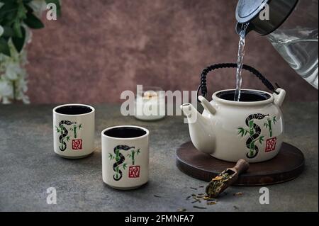 https://l450v.alamy.com/450v/2fmnfa7/from-the-kettle-pour-boiling-water-in-the-teapot-for-the-tea-ceremony-with-an-old-ceramic-service-selective-focus-copy-space-2fmnfa7.jpg