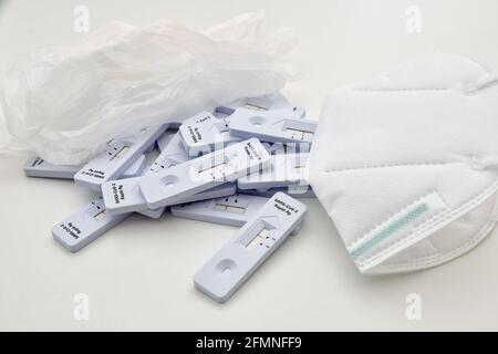 bunch of corony virus rapid antigen test kits laying on laboratory surface, with gloves and protective face mask as medical doctor needs a break. clos Stock Photo