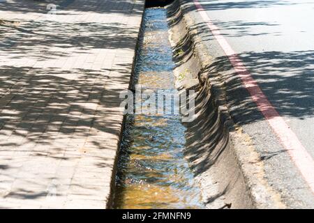 storm water drain or gutter in the street with water running in the channel concept road engineering infrastructure in Stellenbosch Stock Photo