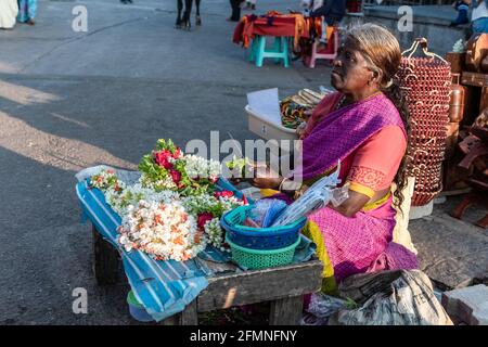 Mysuru, Karnataka, India - January 2019: An elderly female street vendor selling flowers by the roadside in the city of Mysore. Stock Photo