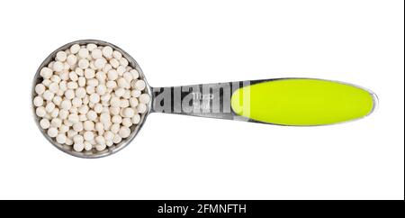 top view of uncooked ptitim (pearl couscous) in measuring spoon cutout on white background Stock Photo
