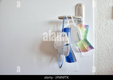 Collection of corona virus disease protective face masks for the whole family hanging on door blue surgical colorful children white ffp2 kn95 Stock Photo