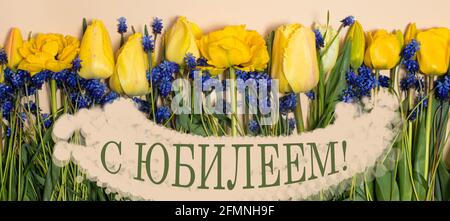 Long horizontal banner yellow tulip flowers with the inscription in Russian Happy Jubilee anniversary. Stock Photo