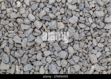 Dry white limestone ballast flat full frame background. Small gray dusty broken macadam stones texture. Viiew from above. Stock Photo