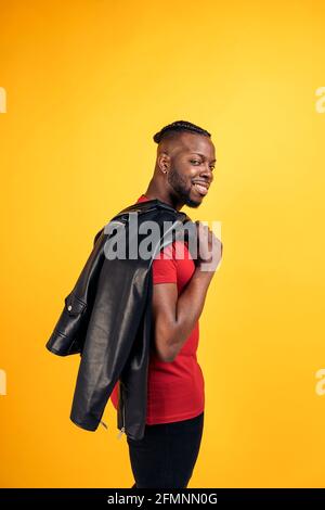 Confident black man wearing black leather jacket smiling and looking at camera in studio shot. Stock Photo