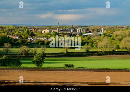 Scenic rural & urban view over flat sunlit farmland fields & Tadcaster town (brewery buildings, houses) - Vale of York, North Yorkshire, England, UK. Stock Photo