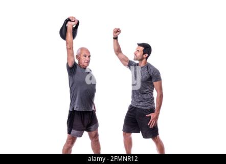 Elderly male client exercising with a fitness trainer, raises dumbbell. On a white isolated background. Stock Photo