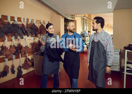 Footwear designer or production manager talking to group of shoe factory workers Stock Photo