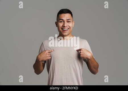 Happy handsome guy smiling and pointing fingers at himself isolated over grey background Stock Photo