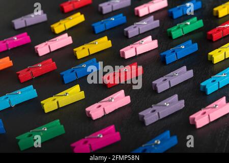 Bright multi-colored clothespins on black background. Diversity. Stock Photo