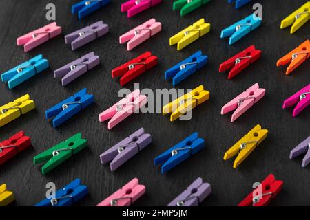 Bright multi-colored clothespins on black background. Variety of choice. Stock Photo