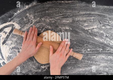 Women's hands rolling out dough for shortbread cookies. Homemade baking. Top view. Stock Photo