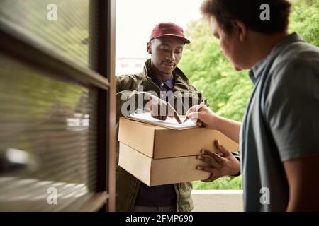 Man signing for a courier delivery at his front door Stock Photo
