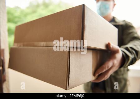 Delivery man holding up packages at a customer's door Stock Photo