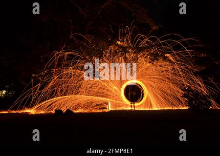 Sparkling photo painting with steel wire in nature at night connected on string with centrifugal movements Stock Photo